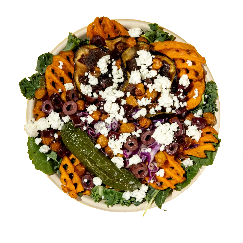 A vibrant salad featuring sweet potato waffle fries, roasted eggplant, and black olives sits alongside crispy chickpeas, kale, and a stuffed pepper. Topped with crumbled feta cheese on a white plate, this colorful dish is perfect for those seeking fresh options at lunch places near me.